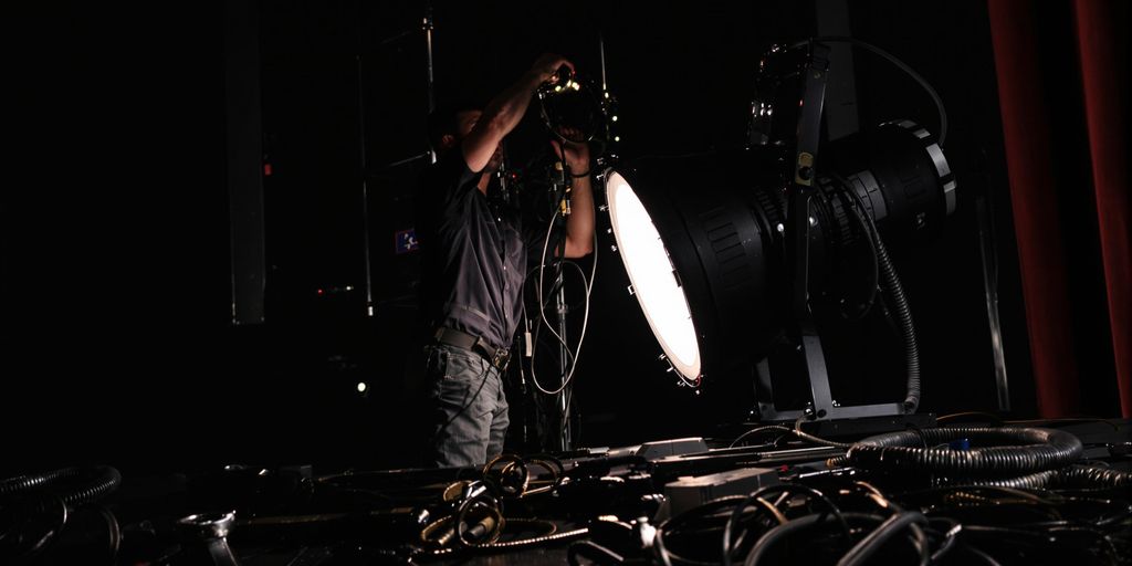 Stage technician, spotlights, tools, theatrical ambiance.