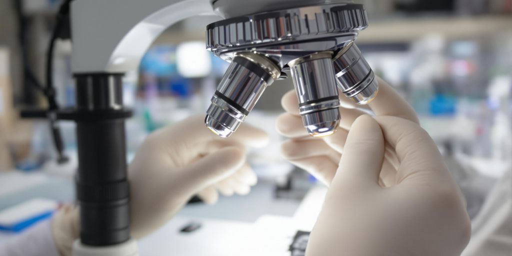 Microscope, medical technologist's hands, laboratory.