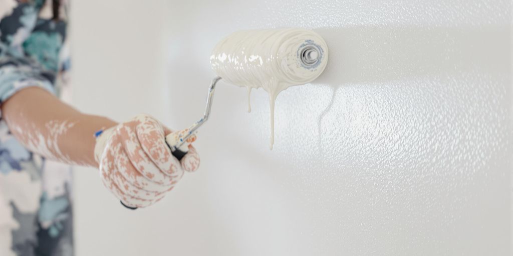 Painter with roller painting a wall.