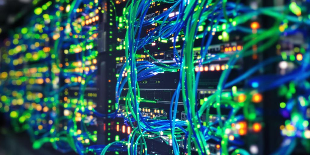 Laptop displaying server racks, network cables, glowing circuits.
