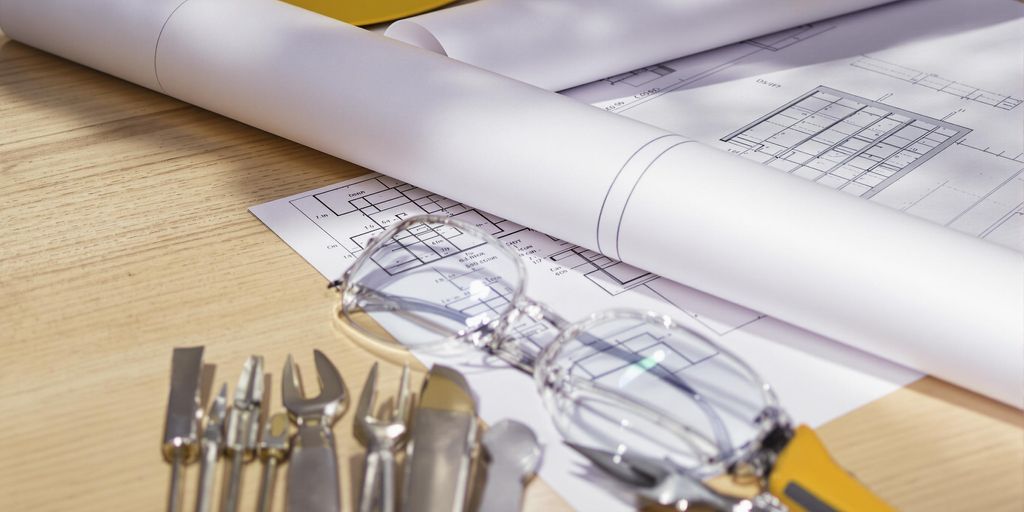 Blueprint, hard hat, safety glasses, drafting tools