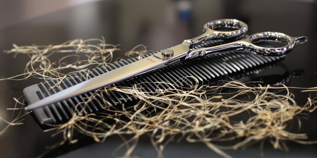 Scissors, comb, and hair strands on a salon counter