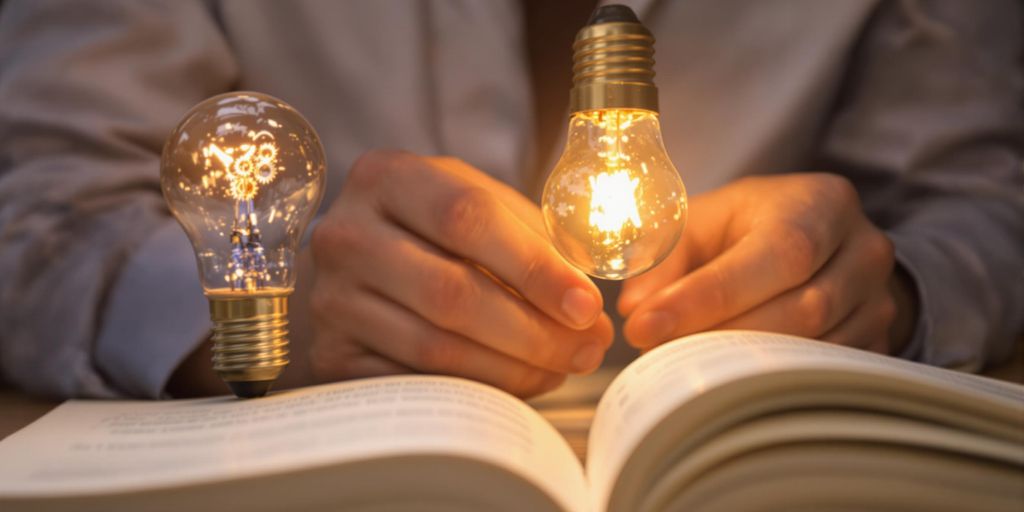 Person solving problems, lightbulb, gears, open book.