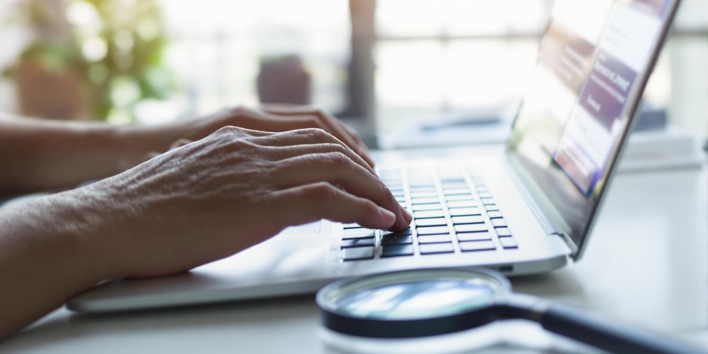 Person typing on laptop, resume on screen