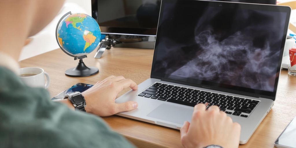 Laptop, coffee, and globe on a wooden desk.