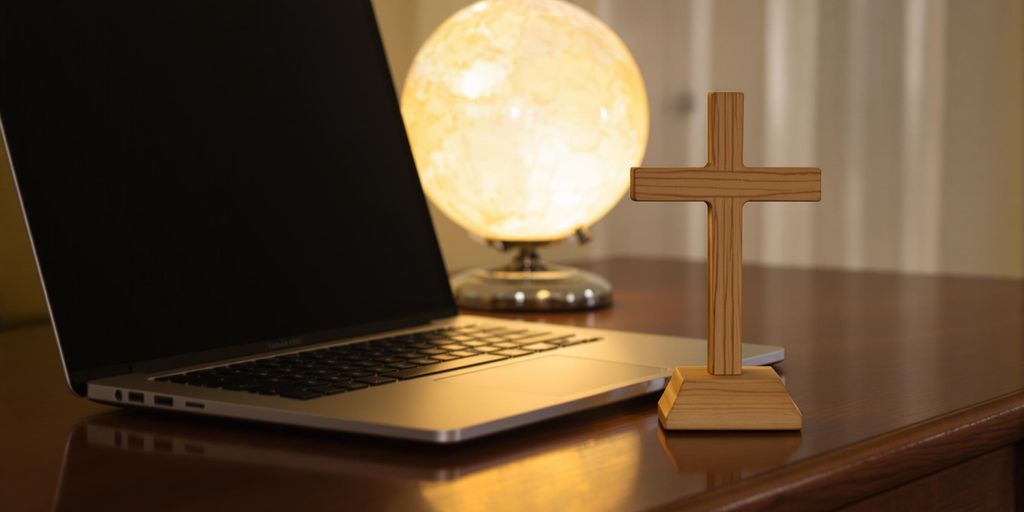 Laptop, cross, and globe on a table.