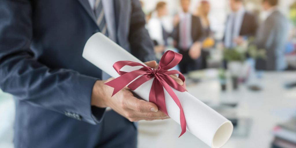 Person holding diploma, smiling confidently at career fair.